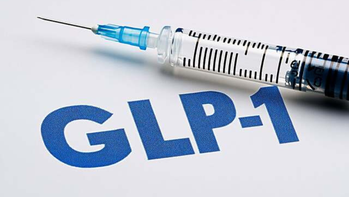 Medical syringe resting beside large blue GLP-1 text on a white background
