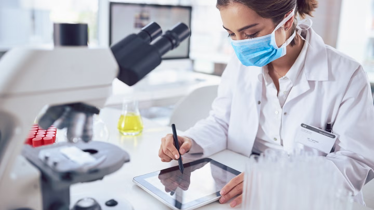 Scientist using a tablet for peptide research in a modern lab with microscope nearby