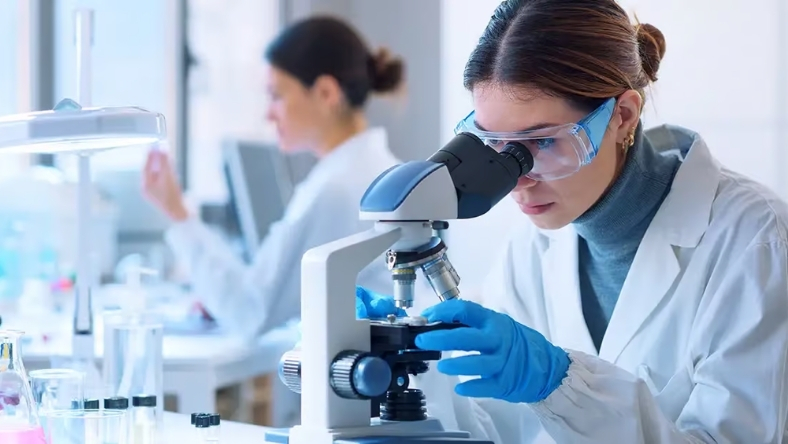 Scientist examining samples under a microscope in a pharmaceutical lab
