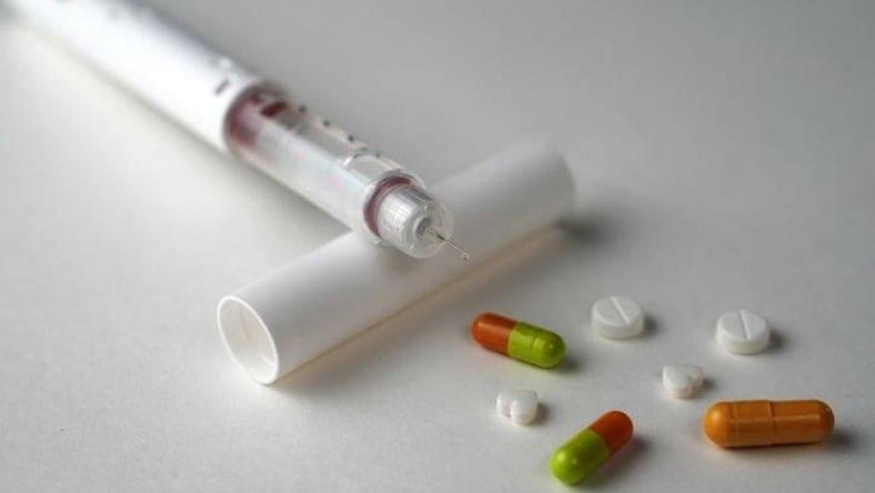 Syringe and assorted capsules and tablets placed on a flat surface
